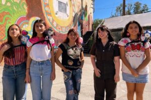 Students with Skobots on their shoulders stand next to Danielle Boyer